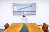 A photo of a training room at R&J Machinery with a large screen display showing a machine's digital menu system