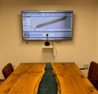 A photo of a training room at R&J Machinery with a large screen display showing a machine's digital menu system